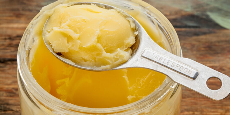jar and measuring tablespoon of ghee - clarified butter