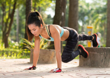 Asian young woman doing plank exercise outdoors