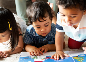Children reading a book on the floor