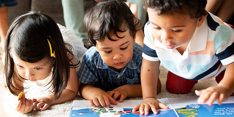 Children reading a book on the floor