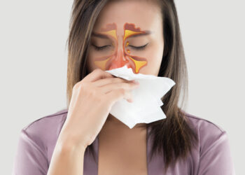 Asian women in satin robes feeling unwell and sinus against gray background. Dust allergies. Flu. People caught cold and allergy.