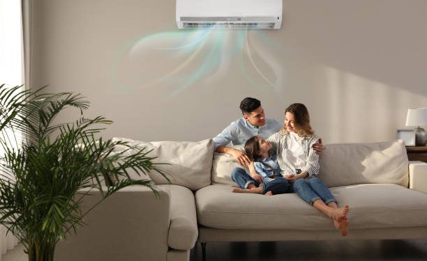 Happy family resting under air conditioner on beige wall at home